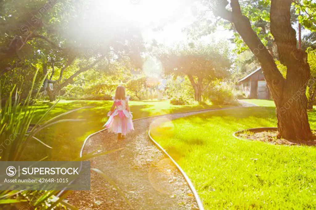 Girl in princess outfit walking on path in sunlight