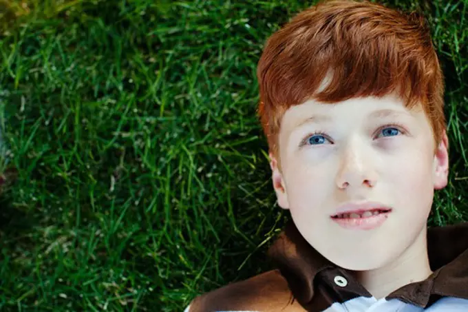 Boy lying on grass looking up