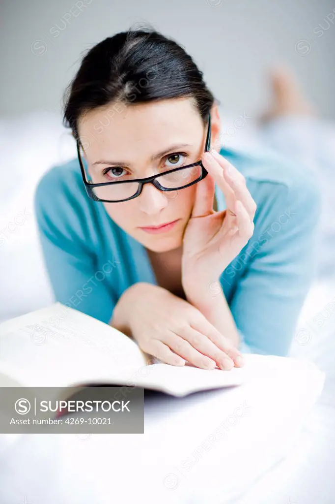 Woman with glasses reading a book.