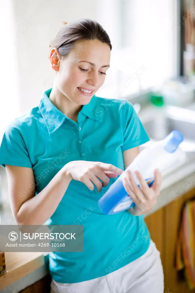 Woman reading the composition of cleaning product.