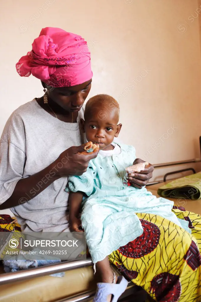 Woman feeding her son with Plumpy nut, peanut-based therapeutic food. Program of ambulatory treatment of malnutrition implemented by a local non-governmental organisation and Action contre la Faim (ACF), an international non-governmental organisation (Action against Hunger). Pipeline hospital, Monrovia, Liberia.