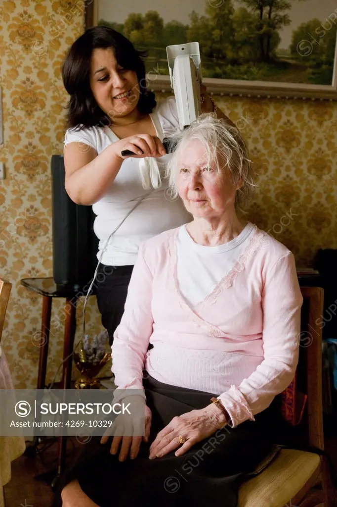 The association SAM AREPA provides home support for elderly poeple. Home care aid assisting elderly woman with Alzheimer's disease, here doing her hair.