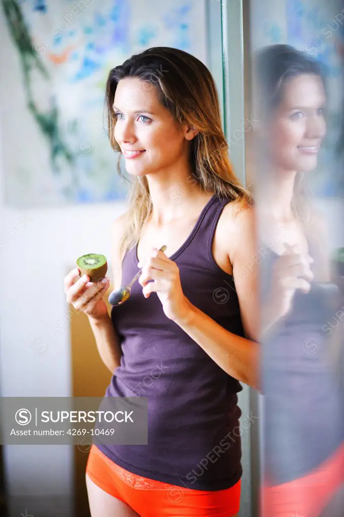 Woman eating kiwi fruit.