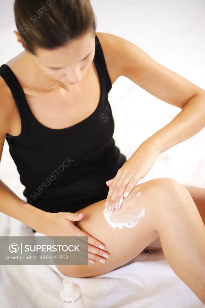 Woman applying cream on her legs.