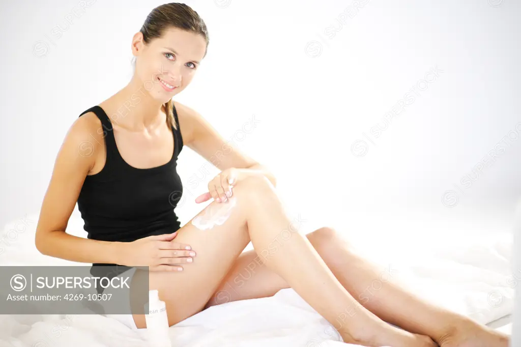 Woman applying cream on her legs.