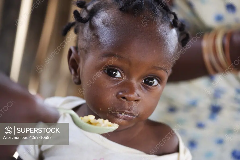 Child suffering from malnutrition tasting a rice-based ordinary meal. Therapeutic Feeding Center in Monrovia, Liberia, implemented by Action contre la Faim (ACF), an international non-governmental organisation (Action against Hunger).