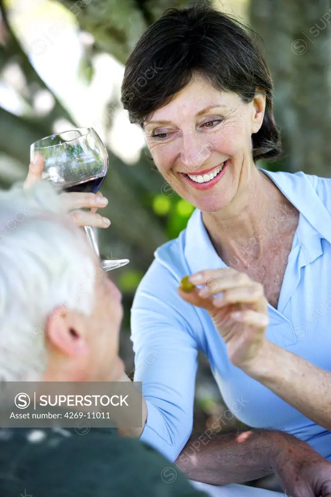 Senior couple drinking wine and eating olives.