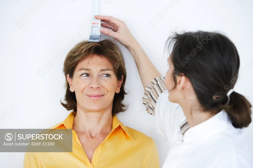A doctor measuring the height of a patient during medical consultation.