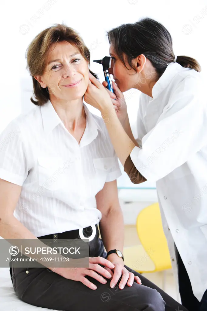 Doctor examining the ears of a patient with an otoscope.