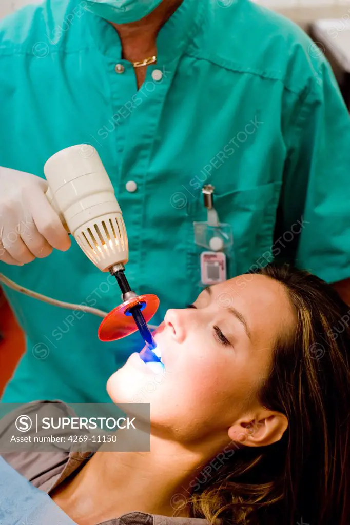 Dentist using ultra violet light to activate teeth withening solution.