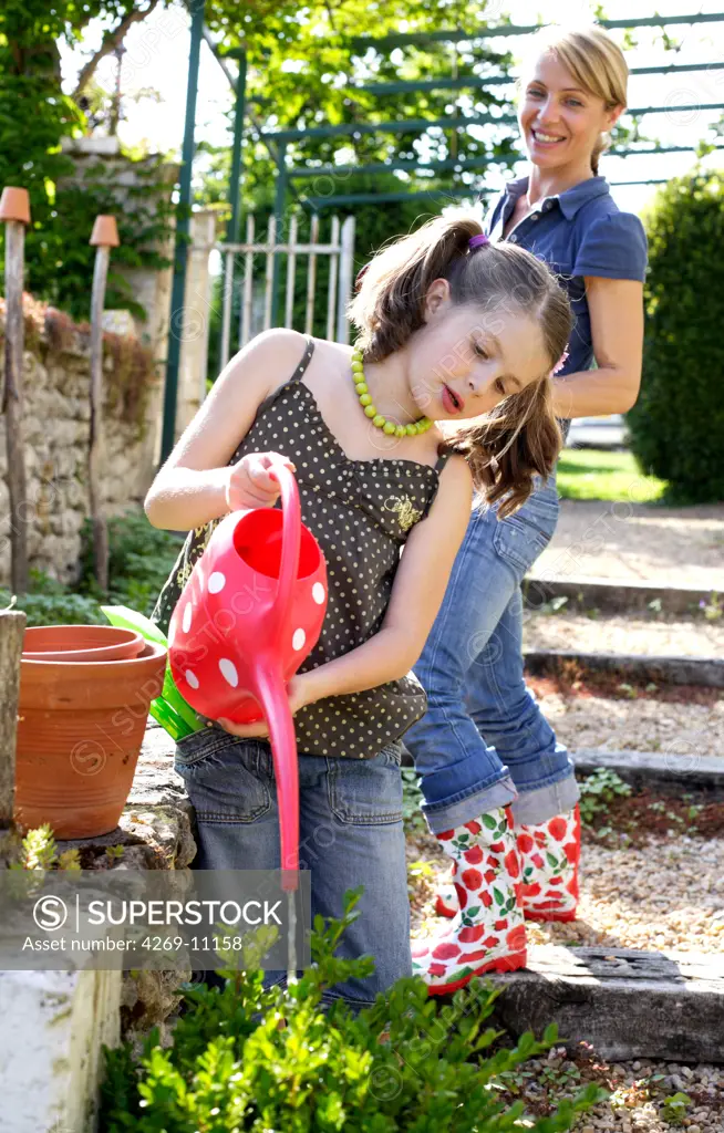 7 years old girl gardening with her mother.