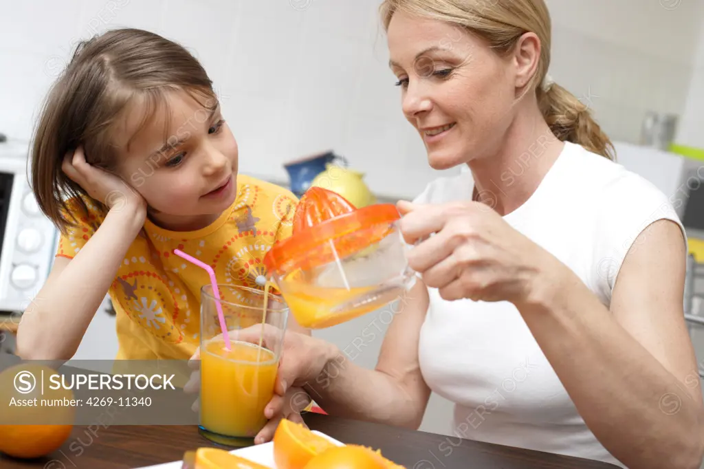 Young girl sqeezing fresh orange juice.