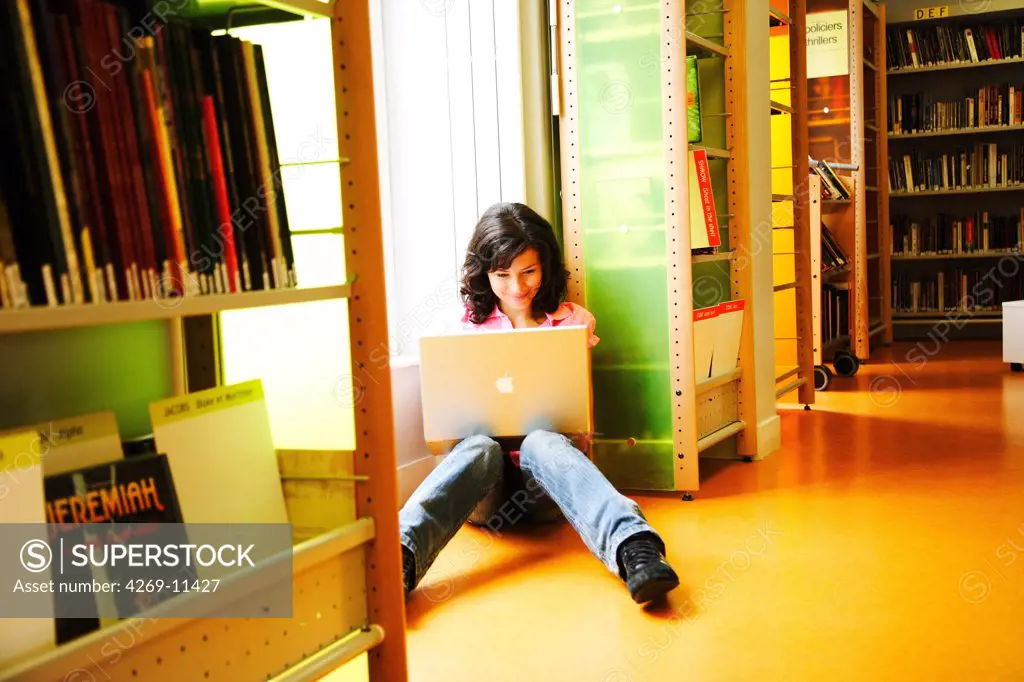Young woman using laptop in library.