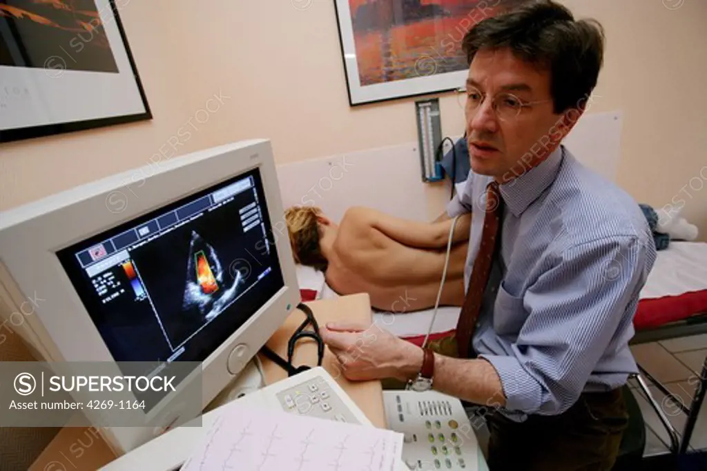Woman having an echocardiography (ultrasound) test to evaluate the health of his heart. The doctor is holding a transducer to his chest in order to produce an image of his heart on the monitor (left). Echocardiography is a technique used to study the heart's structure and function and to diagnose heart disorders.