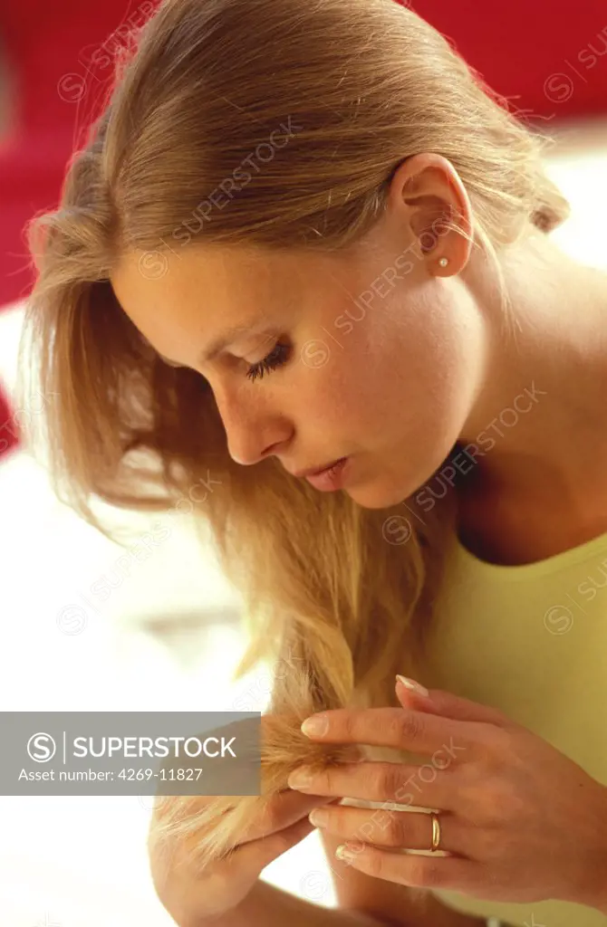 Woman inspecting the tip of her hair.