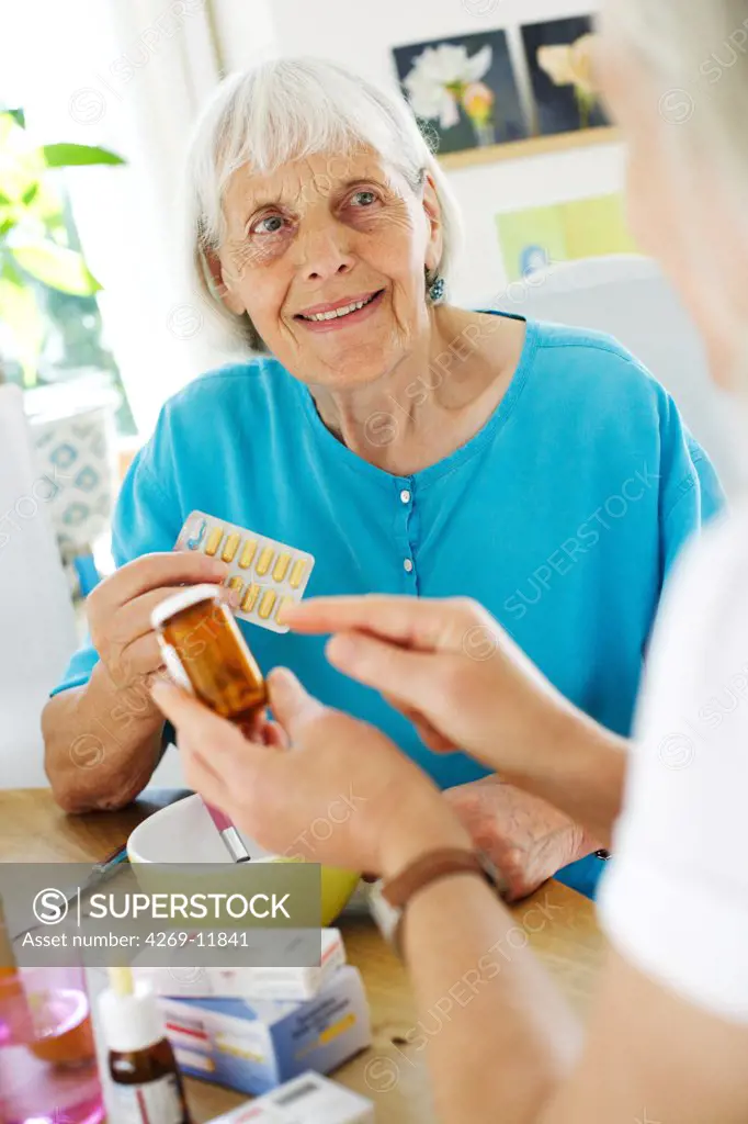 Woman assisting 80 years old woman taking medication.