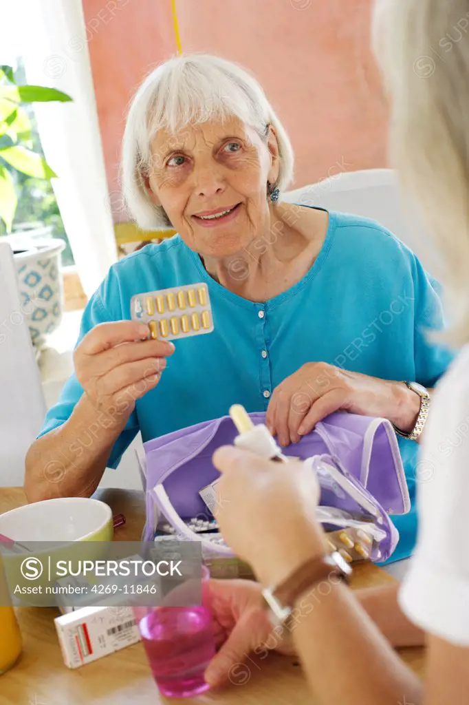 Woman assisting 80 years old woman taking medication.