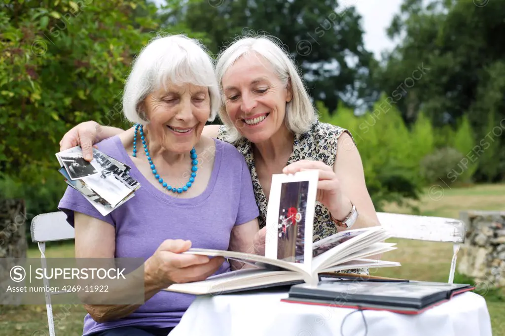 80 years old woman with her daughter looking at photo album.