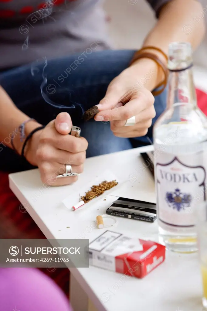 Young person burning hashish to roll a joint.