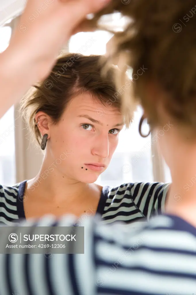 Young woman looking at her hair.