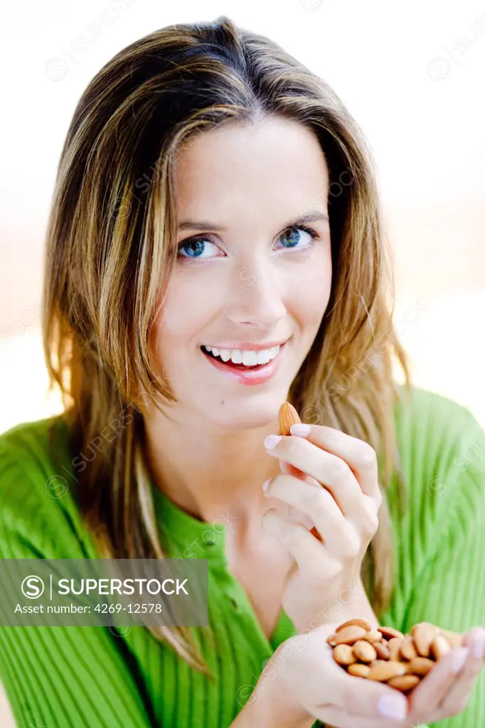Woman eating almonds, rich in omega-3 fatty acids and proteins.