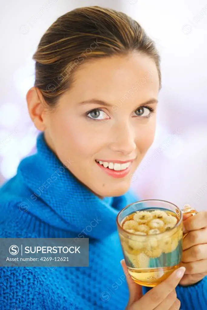 Woman drinking infusion of dry camomile flowers.