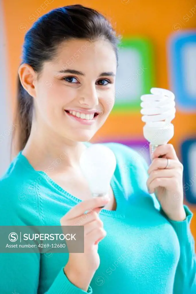Woman holding energy saving lightbulb (right) and incandescent lightbulb (left).