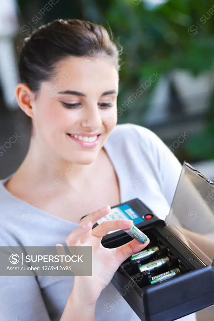 Woman using charger for rechargeable batteries.