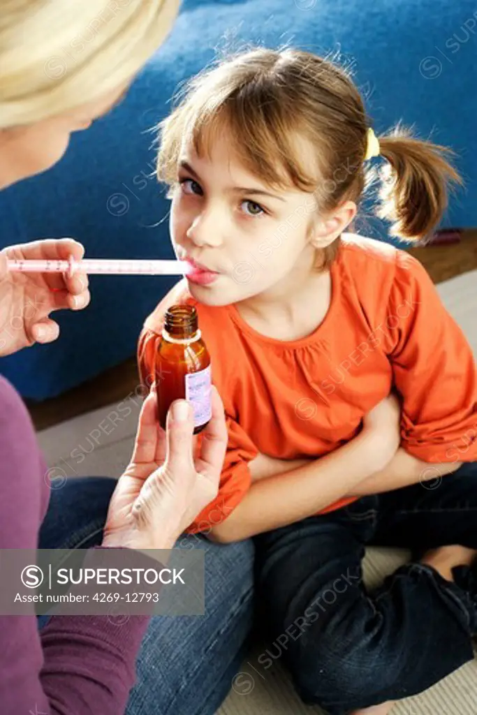 Mother giving her 7 years old daughter syrup with a pipette.