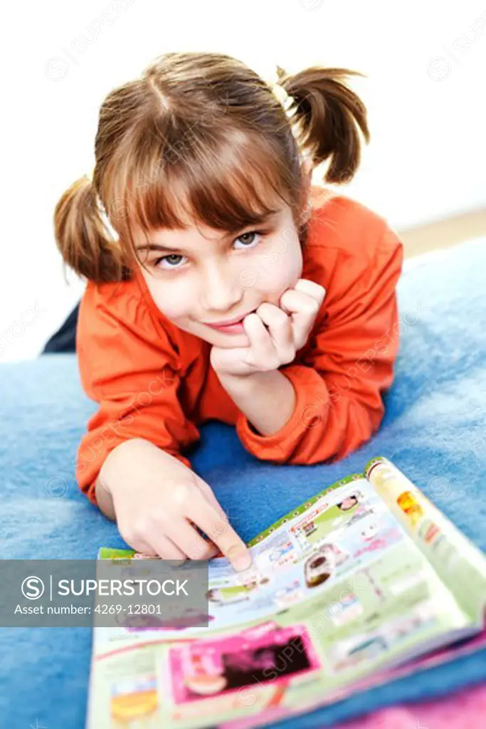 7 years old girl reading toy catalog.