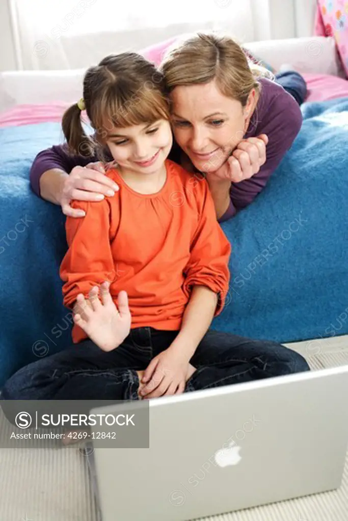 7 years old girl with her mother using laptop computer.