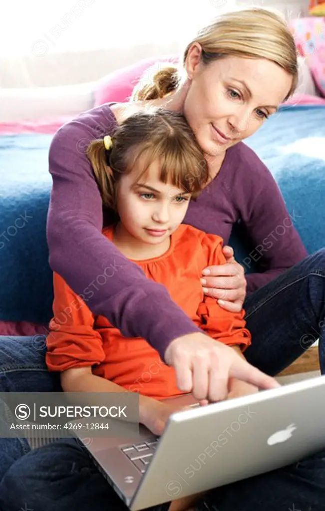 7 years old girl with her mother using laptop computer.