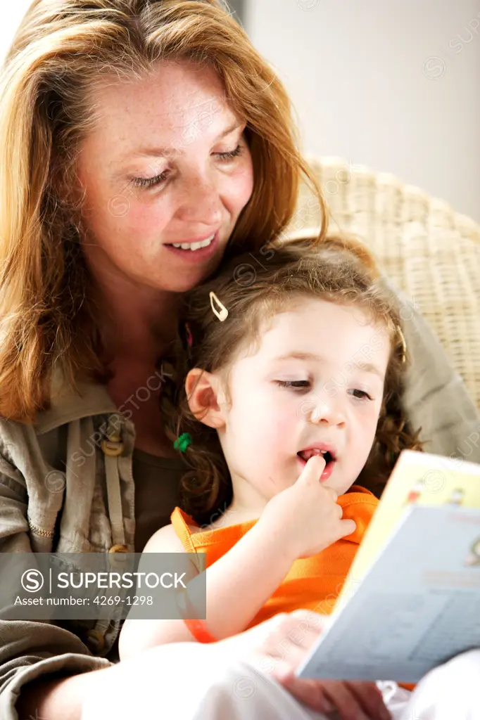 Mother reading a book to her 4 years old daughter.