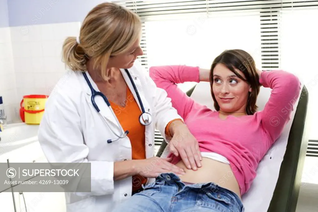 Doctor examining the abdomen of a female patient by palpation.