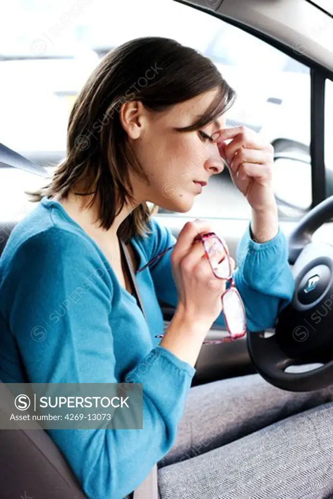 Woman with headache in her car.