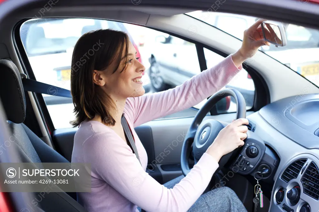 Woman adjusting rearview mirror.