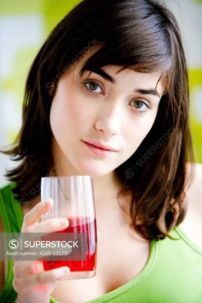 Woman drinking a glass of cranberry juice for cystitis prevention.