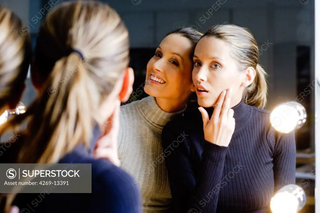Twin sisters looking in mirror.