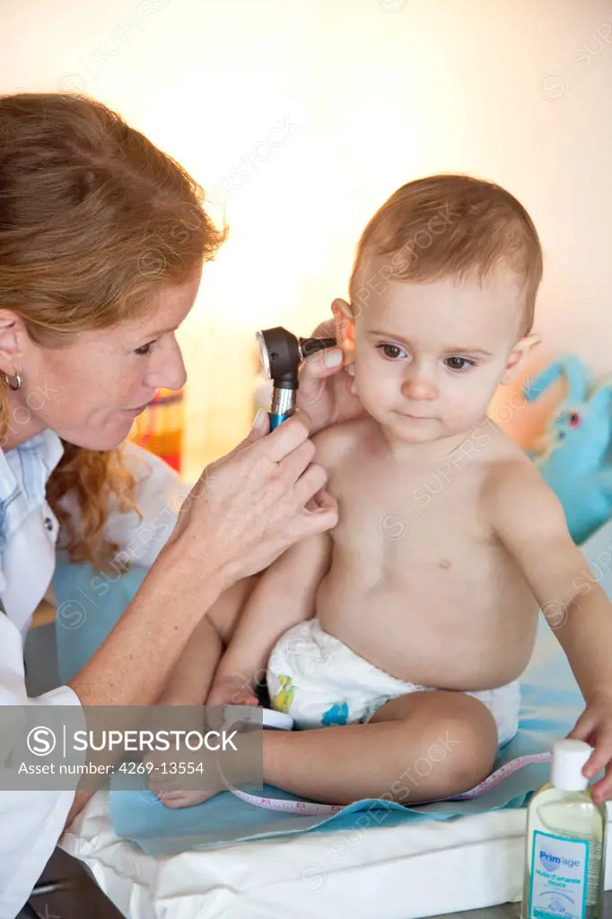 Pediatrician examining the ear of a 15 months old baby with an otoscope.