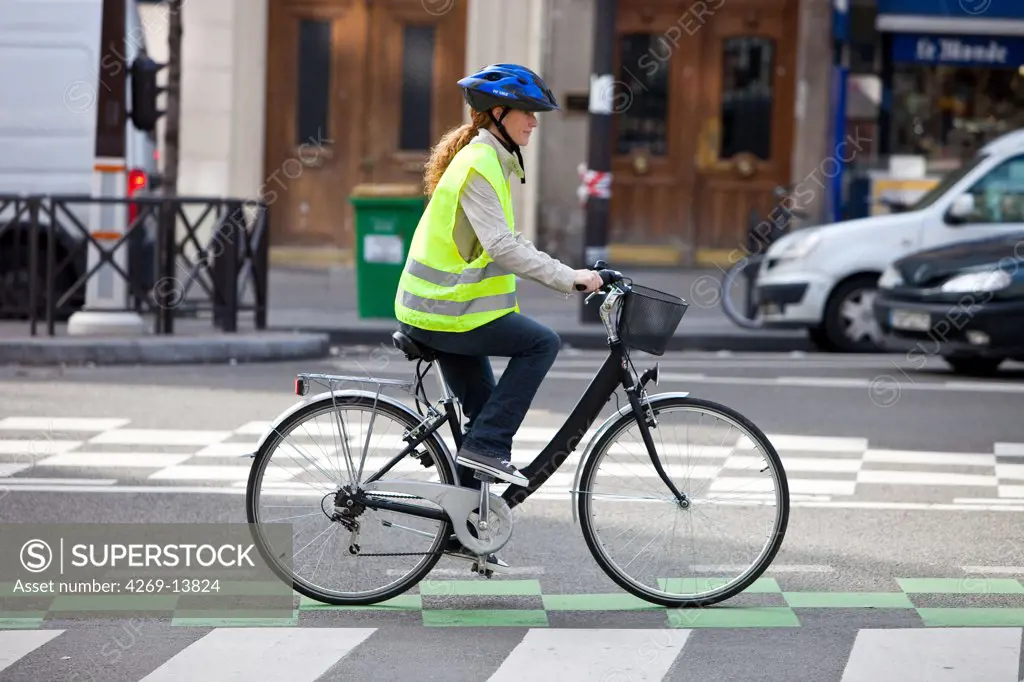 Woman riding a bicyle in a urban environment.