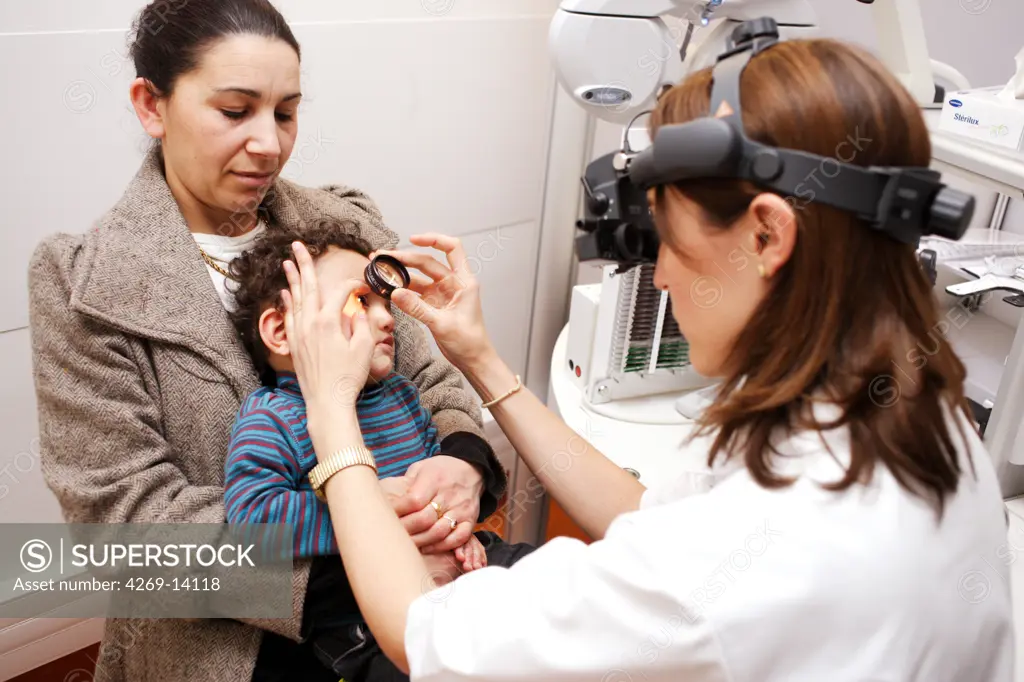 Ophthalmologist examining the interior of the eye of a 16 months old baby with an ophthalmoscope. Department of Pediatric Ophthalmology, Limoges hospital, France.