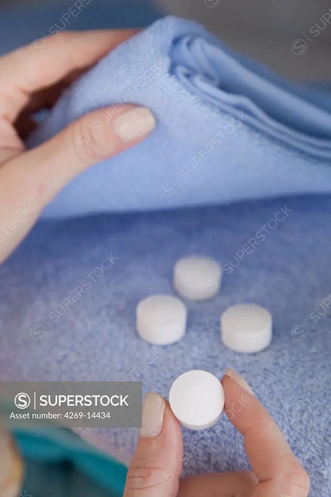 Woman placing mothballs (naphtalene) in her clothes.