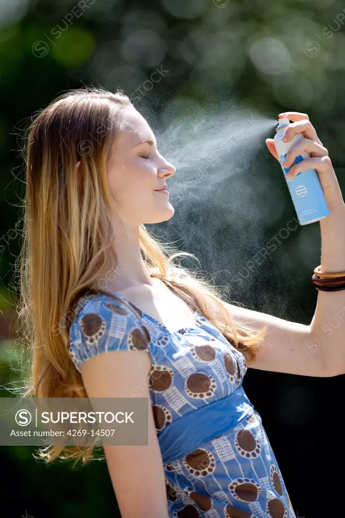 Woman spraying water on her face.