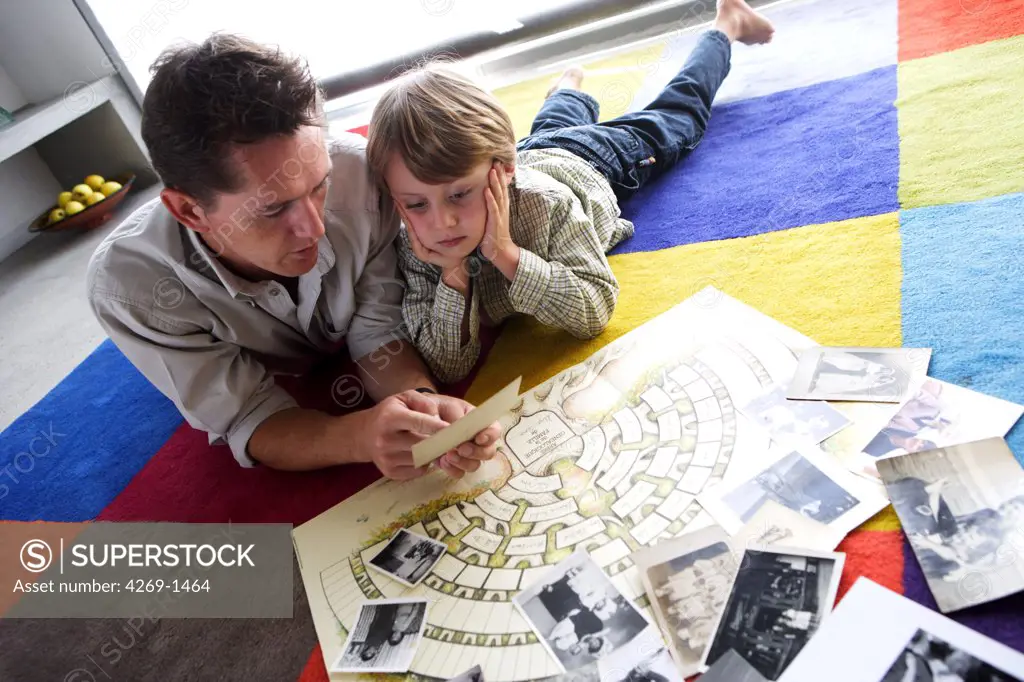 A father and his 5 years old son are watching the family tree and photos of relatives.