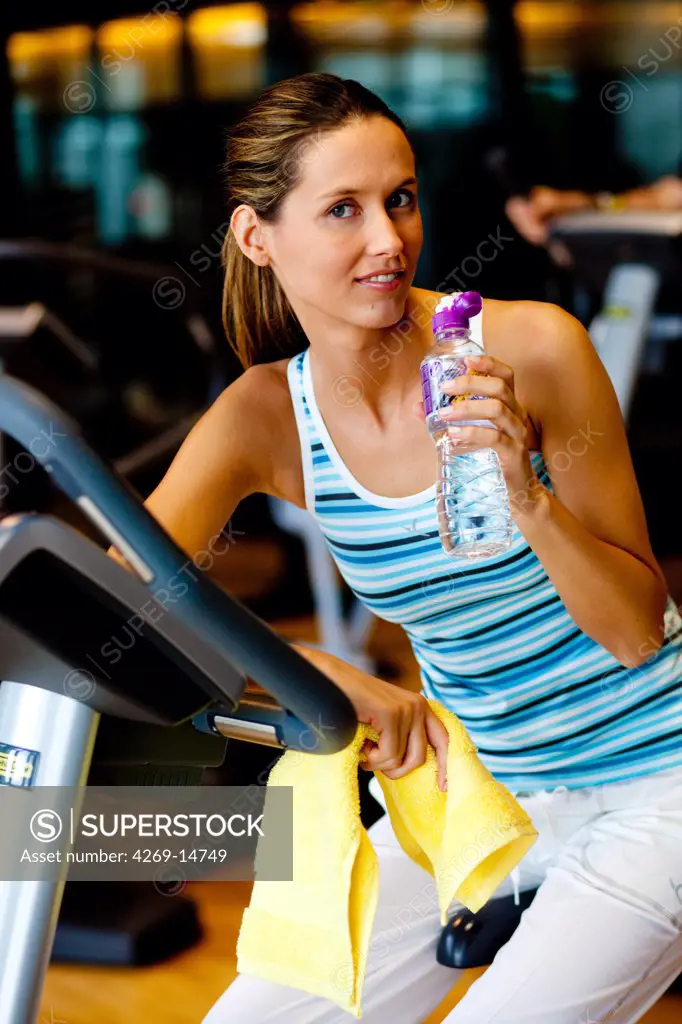 Woman drinking mineral water at the gym.