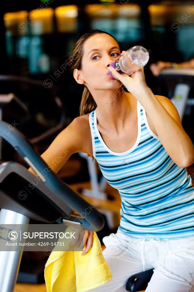 Woman drinking mineral water at the gym.