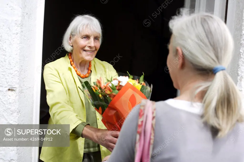 Elderly woman receiving a bouquet of flowers.