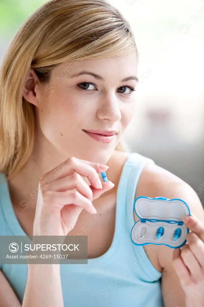 Woman taking Alli medicine. Alli is a half-dose version of the diet drug Xenical (Orlistat) produced by GlaxoSmithKline (GSK). First anti-obesity drug, available in pharmacy without prescription in France from May 6 2009.