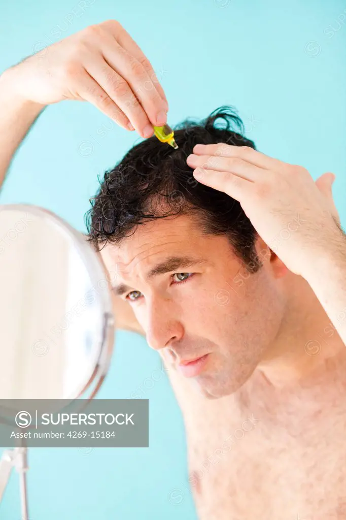 A man uses hair lotion to prevent loss of hair.
