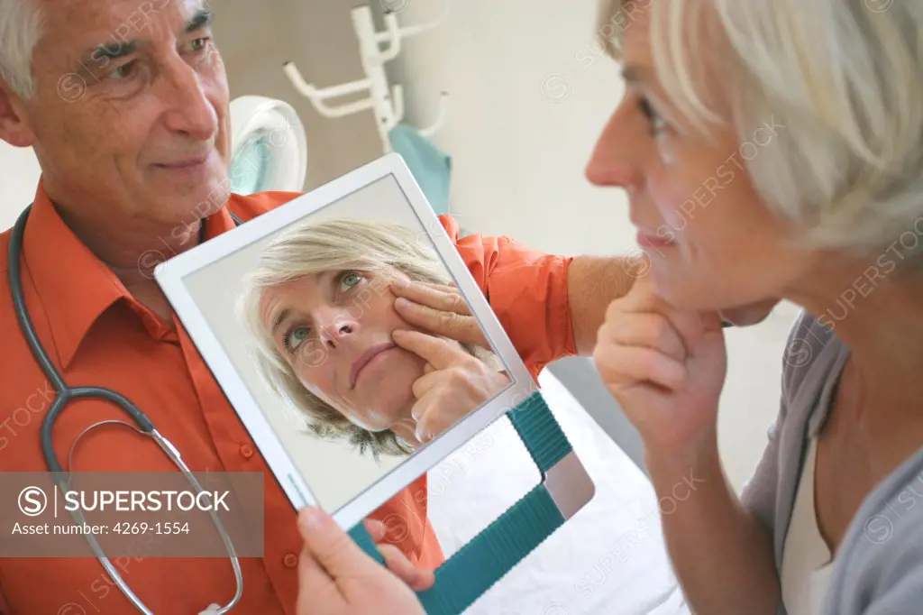 Aesthetic medicine : a doctor talks with a 50 years old patient about the possible anti-aging interventions (botox injections, plastic surgery etc.), or shows her patient the results after intervention.